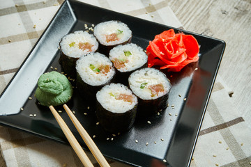 Sushi roll with salmon on a black plate on a wooden background. Japanese food. Seafood