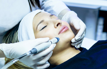 Facial cleansing, vacuum hydro-peeling. Young woman enjoying a radiant face in a beauty salon,...
