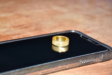 gold ring placed on a smartphone on wooden table