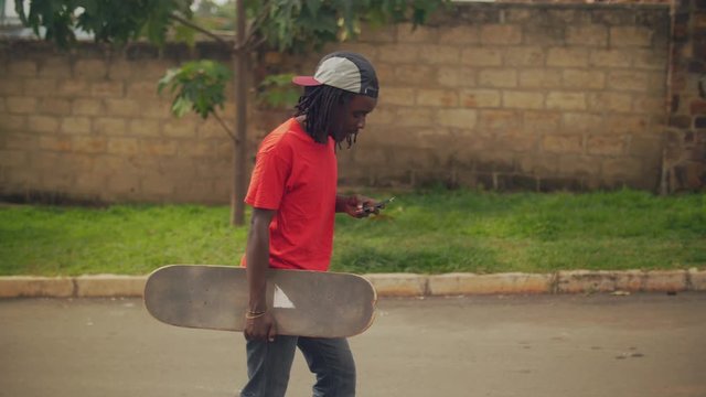 skateboarder walking in the street using cell phone slow motion shot