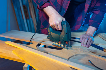 Joiner. The master works with an electric jigsaw. Cutting a piece of plywood. Hand joiner's tools. The cutting of wood. The work of the joiner. Joinery.