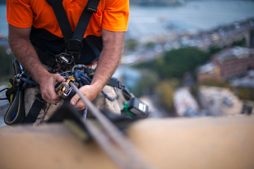 Close up pic of male rope access job industrial worker, using a working safety device descender on...