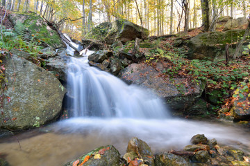 La cascata tra le rocce del bosco in autunno