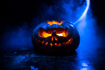 Close up view of scary Halloween pumpkin with eyes glowing inside at black background. Selective...