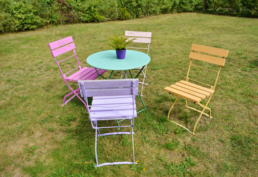 Beautiful colored vintage chairs and garden table outdoor on a green grass