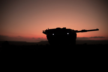 War Concept. Armored vehicle silhouette fighting scene on war fog sky background. American tank at sunset.