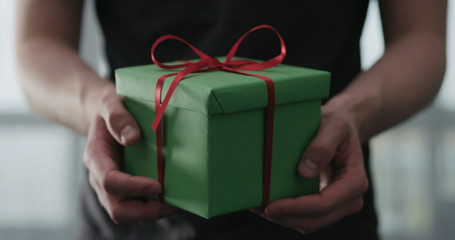 young man show green paper gift box with red ribbon