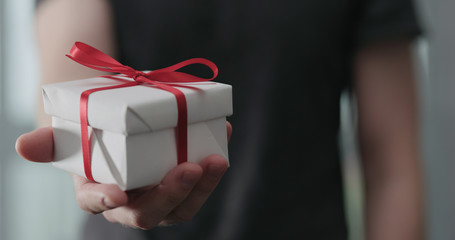 young man show white paper gift box with red ribbon