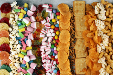 Salty snacks. Pretzels, chips, crackers and candy sweets on table