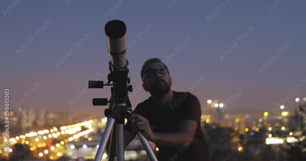 Canvas Prints astronomer with a telescope watching at the stars and moon with blurred city lights in the backgroun