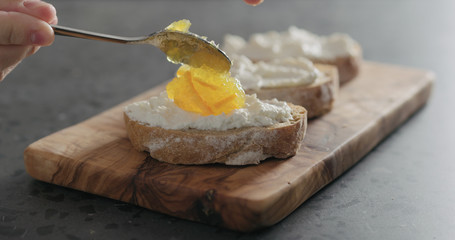 man hand making sweet bruschetta with orange marmalade and ricotta