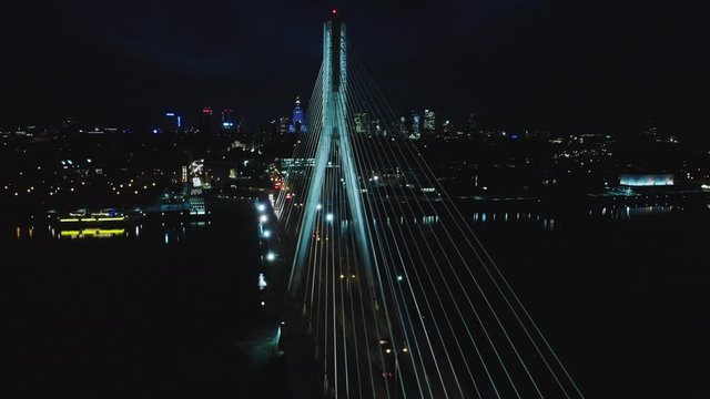 Aerial circle shot of cinematic evening view at Swietokrzyski bridge Warsaw and illuminated cityscape