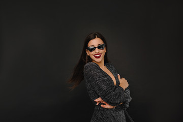 Close-up indoor photo of pretty european woman in sunglasses posing on black background. Dansing, happiness, party