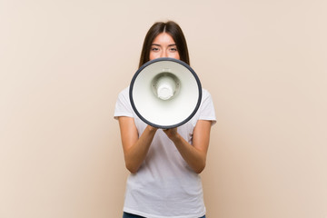 Pretty young girl over isolated background shouting through a megaphone