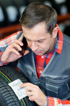 male worker looking at sticker showing reference for tyre