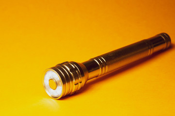 Metal led flashlight on a yellow background