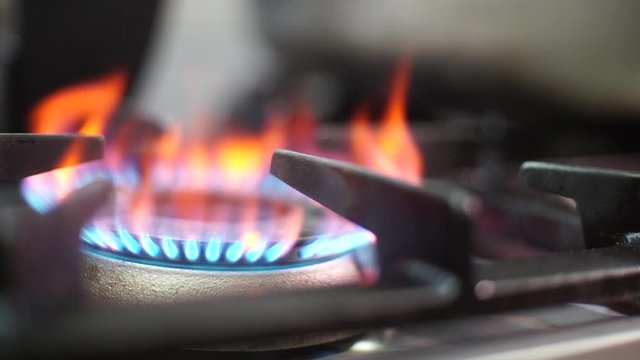Hand of a man starting fire on the gas stove burner in the kitchen close up. Slow Motion