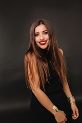 Naklejka premium Smiling happy caucasian woman with dark hair and holiday make up having fun over dark background