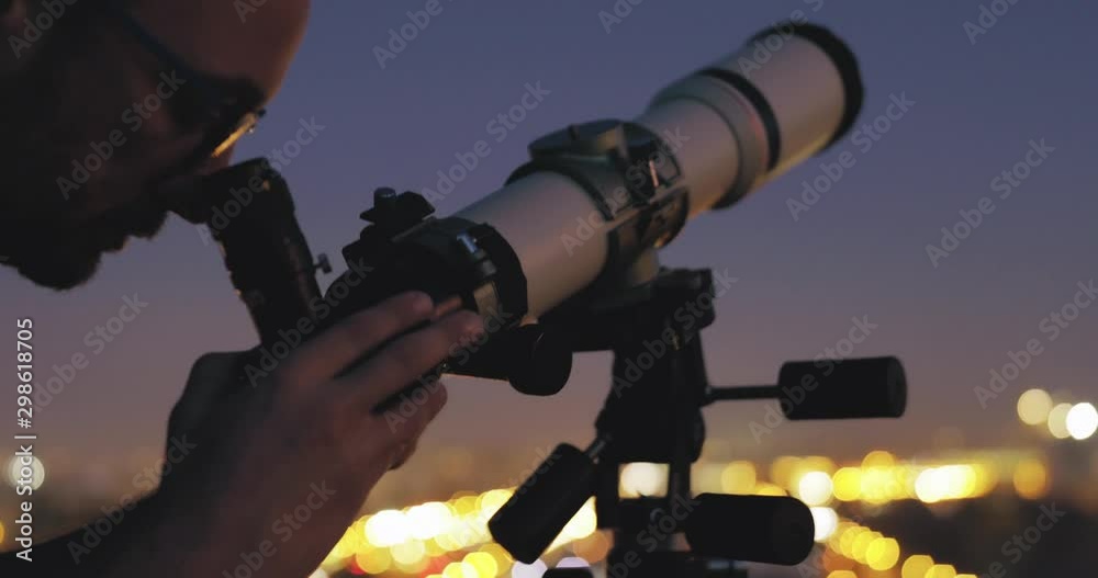 Canvas Prints astronomer with a telescope watching at the stars and moon with blurred city lights in the backgroun