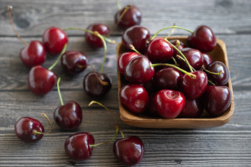 Ripe fresh cherries in a wooden bowl. Food background. Red juicy cherry berry on grey wooden background. Cherries in a dish close-up.