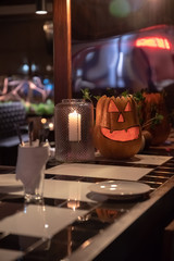 A pumpkin in the form of a smiling face is standing on the bar on the eve of the helloween holiday