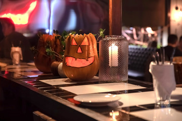 A pumpkin in the form of a smiling face is standing on the bar on the eve of the helloween holiday