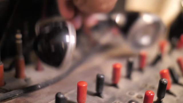 Close up on hand picking up head set from control panel in telephone exchange