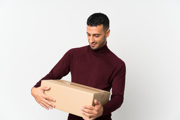 Young man over isolated white background holding a box to move it to another site