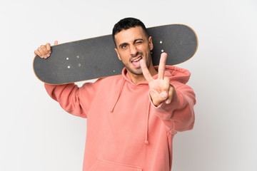 Young man over isolated white background with skate and making victory gesture