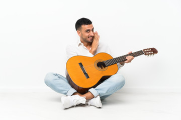 Obraz premium Young man sitting on the floor with guitar whispering something