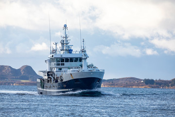 Naklejka premium Fishing boat through Brønnøysundet to the fishing fields in northern Norway