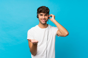 Naklejka premium Young handsome man over isolated blue background working with headset
