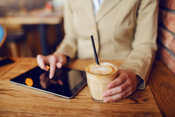 Close up of caucasian woman sitting in cafe, using tablet and holding coffee.