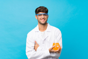 Young handsome man over isolated blue background with a scientific test tube © luismolinero
