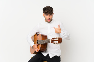 Young handsome man with guitar over isolated white background with surprise facial expression