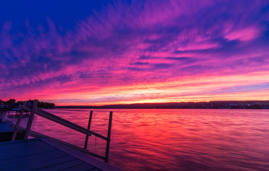 Fototapeta na wymiar Vivid ultra violet sunset over calm water at Silver Lake, NY State