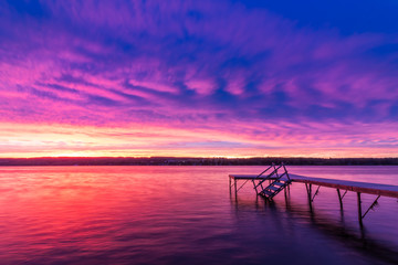 Fototapeta na wymiar Vivid ultra violet sunset over calm water at Silver Lake, NY State