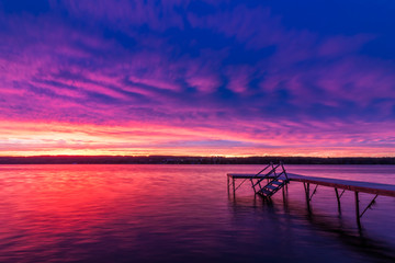 Naklejka na ściany i meble Vivid ultra violet sunset over calm water at Silver Lake, NY State
