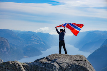 Obraz premium Woman with a waving flag of Norway on the background of nature