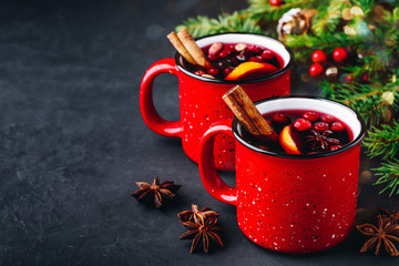 Traditional Christmas Mulled Wine drink with cranberries, orange slices and spices in red mugs