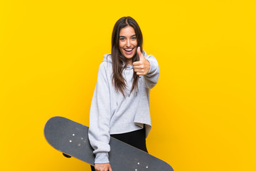 Young skater woman over isolated yellow background with thumbs up because something good has...