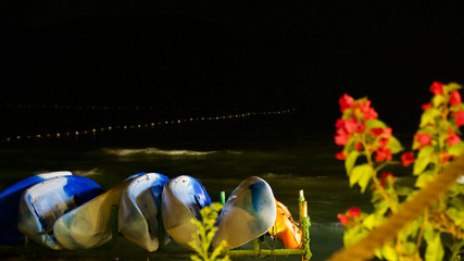 Striped canoes by the sea and glowing city lights at night