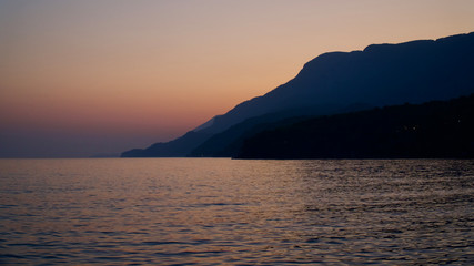 Sunset at the Aegean Sea, palm trees and people having fun at sea