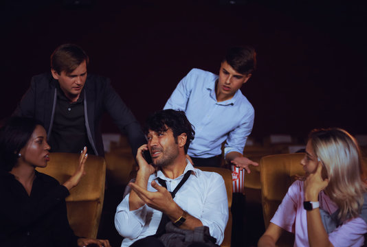 Man talking with mobile phone in theater bad manner  and another person unhappy with him