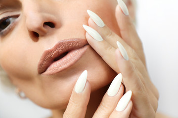 Portrait of a woman with clean healthy skin and a long manicure with milk nail Polish close-up.