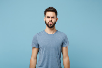 Young perplexed confused irritated man in casual clothes posing isolated on blue wall background, studio portrait. People sincere emotions lifestyle concept. Mock up copy space. Looking camera.
