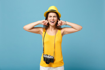 Traveler tourist woman in yellow summer casual clothes hat with photo camera isolated on blue background. Female sad passenger traveling abroad to travel on weekends getaway Air flight journey concept