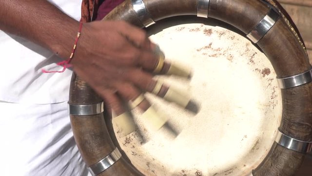 A barrel-shaped double-headed drum instrument. A guy is playing the instrument .
