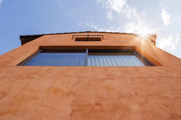 Uprisen angle view of resident with orange clay wall and blue sky in background.