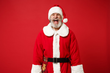 Fototapeta na wymiar Frustrated elderly gray-haired mustache bearded Santa man in Christmas hat posing isolated on red background. New Year 2020 celebration holiday concept. Mock up copy space. Scream keeping eyes closed.